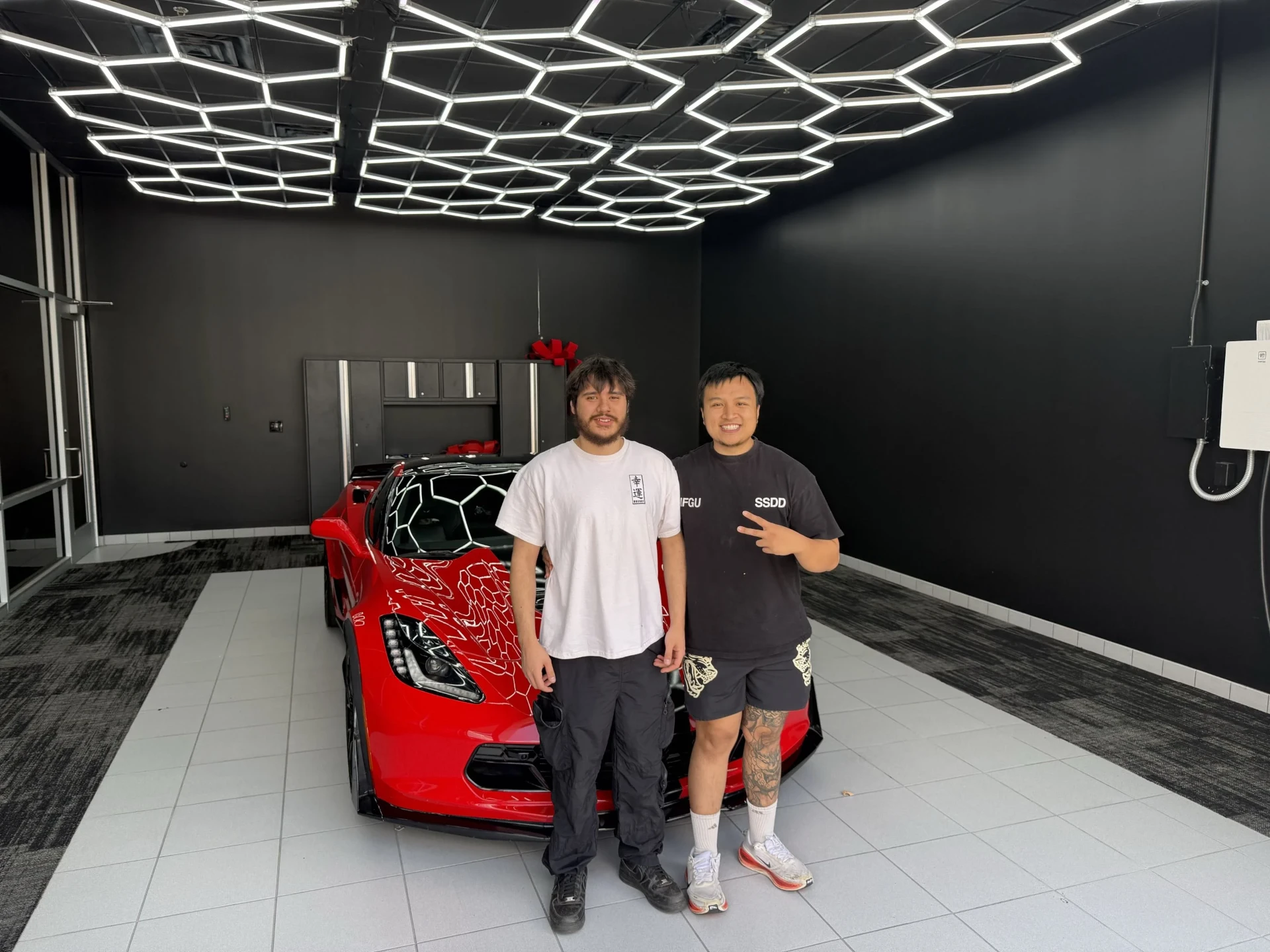 EcomOptimized student with his red C7 Corvette in a showroom